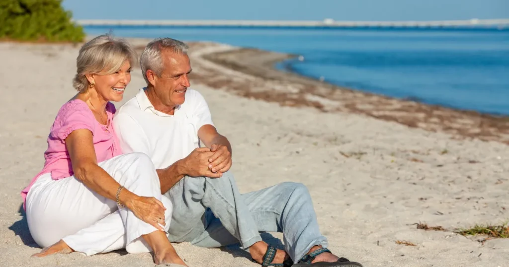 Happy older couple sitting together on the beach