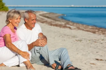 Happy older couple sitting together on the beach