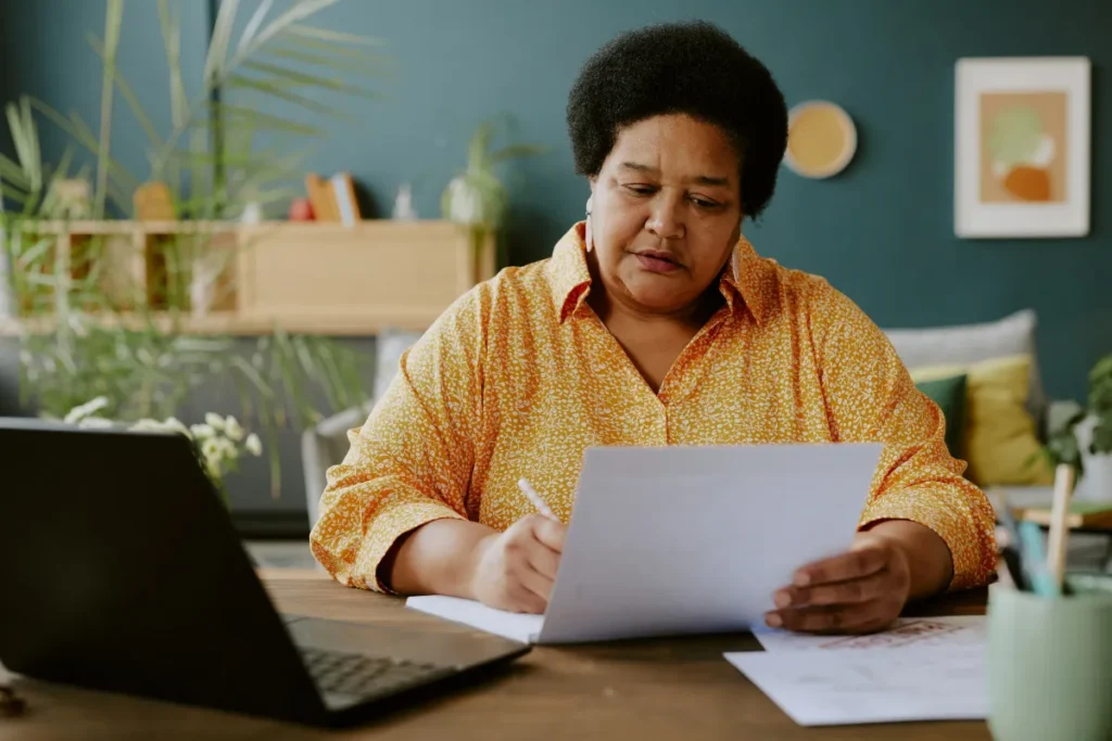 Older woman reviewing documents on a laptop