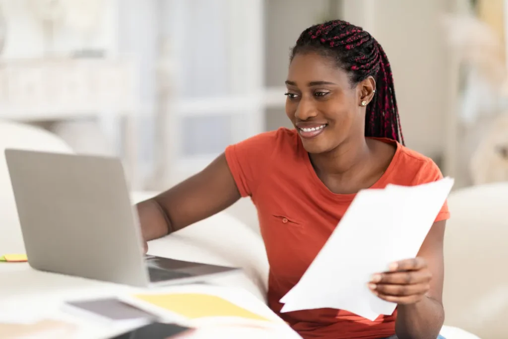Woman smiling while working with laptop and papers