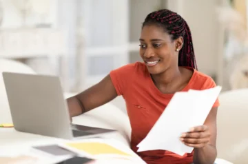Woman smiling while working with laptop and papers
