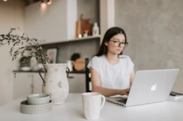 Woman working on laptop in home kitchen